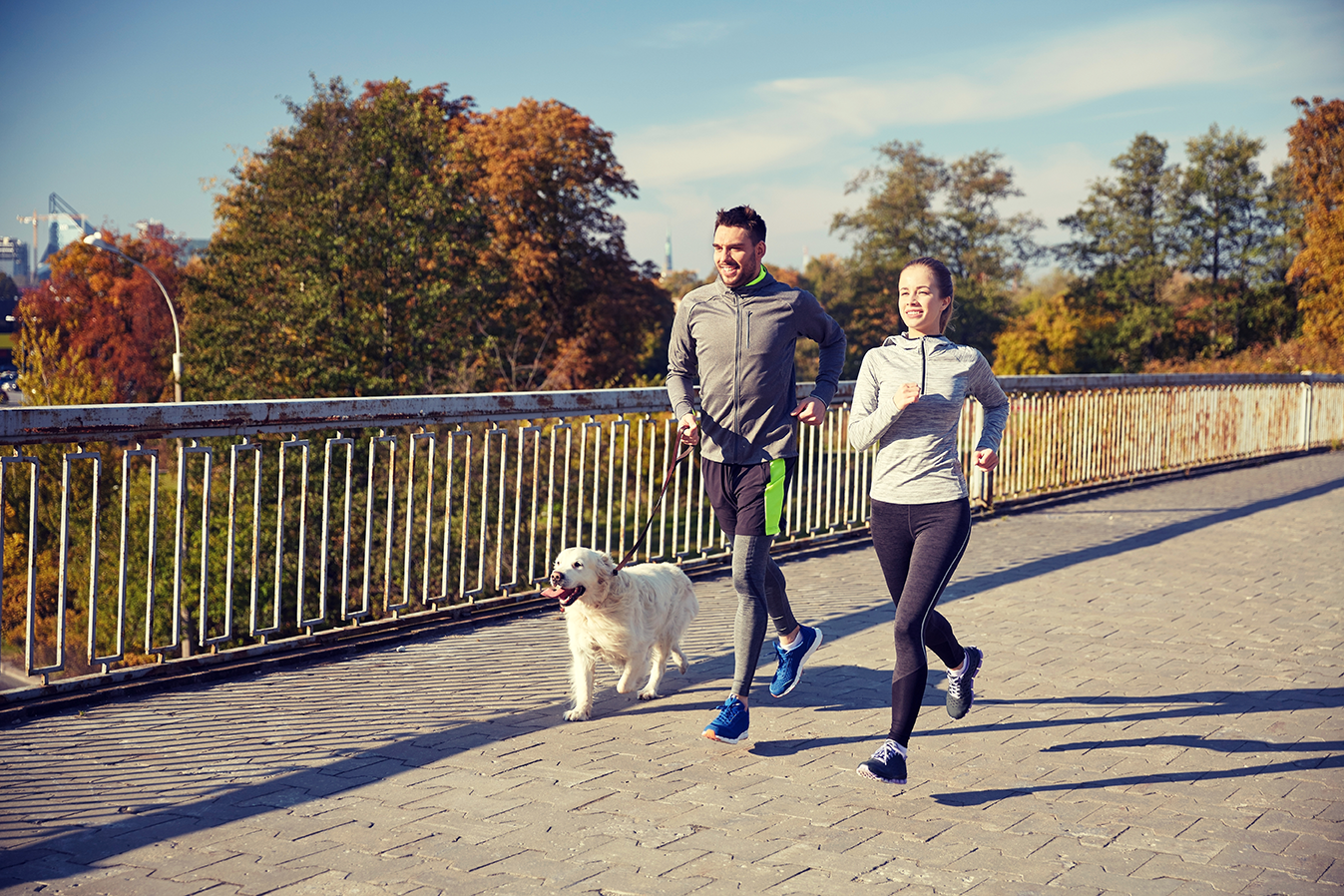 A man and a woman running with their dog